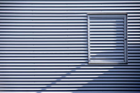 The detail of a modern facade of corrugated metal with a grate window.                          の写真素材