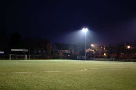 The green lawn of a football field at night is illuminated by floodlights.                           の写真素材