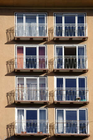 The railings of small balconies of an apartment building cast shadows.                   