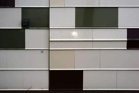 A modern house facade made of metal panels with a wall light.                              