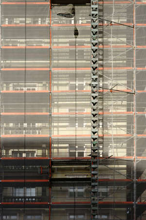 The close-up of a scaffolding with pillars and safety nets as well as a goods lift.                 