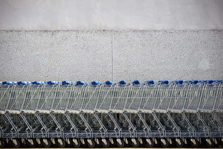 Shopping carts put together in a row in front of the bright wall of a shopping mall.              の写真素材