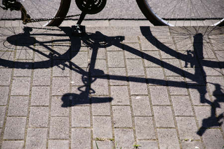 A parked bicycle casting a shadow on the sidewalk.                       の写真素材