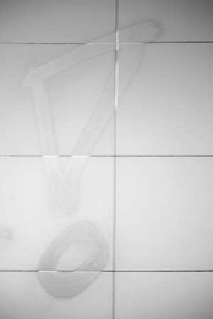 A sprayed silver exclamation mark on a light tile wall.                       の写真素材