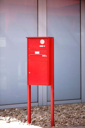 A standing bright red mailbox with a bell and handsfree.