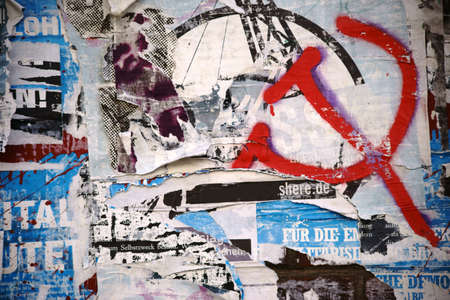 The close-up of a billboard with torn scraps of paper from posters and billboards as well as sprayed...