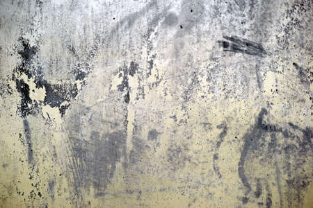 The close-up of a yellow wall with black spots of spilled paint on the wall.
