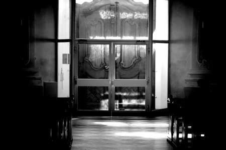 Sunlight falls in the dark room of a church with the silhouettes of prayer rows.のeditorial素材