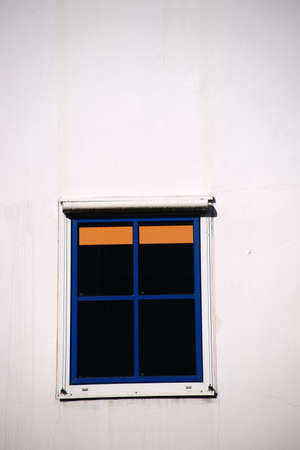 An abstract window with blue window frame and orange venetian blind in the sunlight.の写真素材