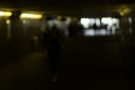 The dark silhouettes of travelers in a station tunnel in low light.の写真素材