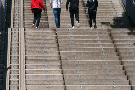 The legs and feet of a group of young people going up an outdoor staircase.の写真素材