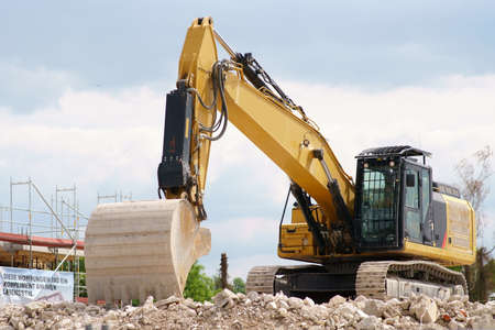 A non-working excavator stands on the rubble heap of a construction site.の写真素材