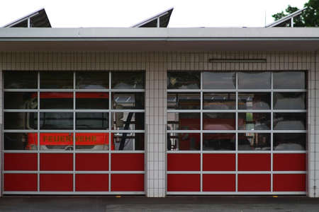 Two fire engines are behind the Plexiglas panes of a garage of the fire department.