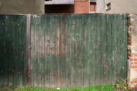 An old wooden fence with faded paint and rusty hinges.の写真素材