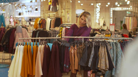 Woman sorts things out on a hanger in a store
