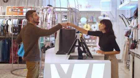 Girl gives a shopping bag to a man with smile