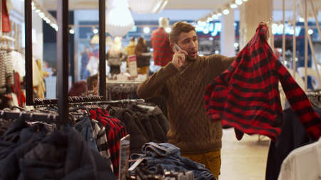 Man chooses clothes and talk on phoneの写真素材