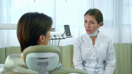 Doctor takes off a mask while talking with a patientの写真素材