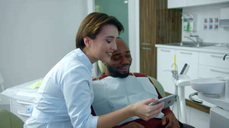 Doctor and patient look on the phone and laughsの写真素材