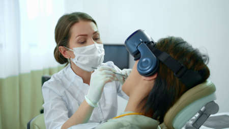 Dentist works, her patient in virtual reality glassesの写真素材