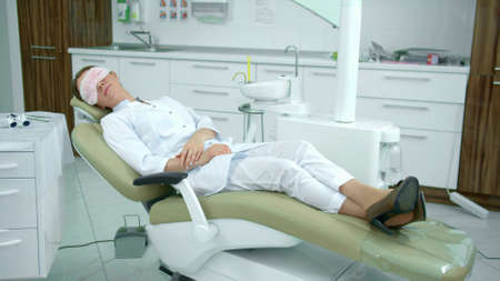 Tired doctor sleeps on a dental chairの写真素材
