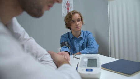 Boy sit in cabinet of hospital, doctor take his blood pressure