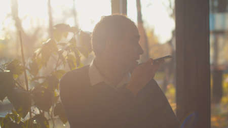 Man sit in cafe and record voice message on phone