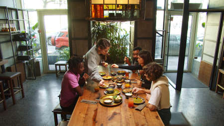 Company of friends meet in a cafe, they eat foodの写真素材