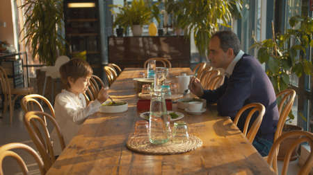 Man and boy eat and talk in cafeの写真素材