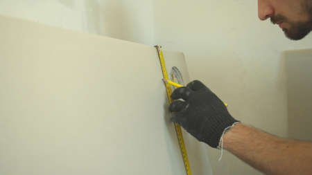 Repairman in uniform measures a length of the wall の写真素材