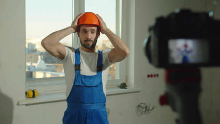 Slow motion, builder puts on helmet and talks on camera