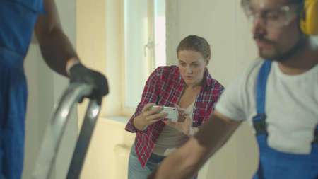 Builders work and woman makes a photo on the phoneの写真素材