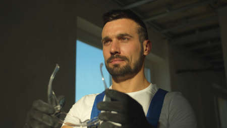 Smiling builder stands and puts on protective glassesの写真素材