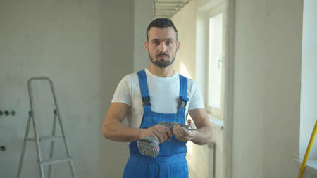 Builder stands and looks at the screwdriver
