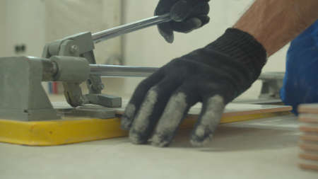 Close up, man in uniform and protective gloves cuts a tile