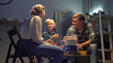Parents and boy work with pottery wheel in the workshop