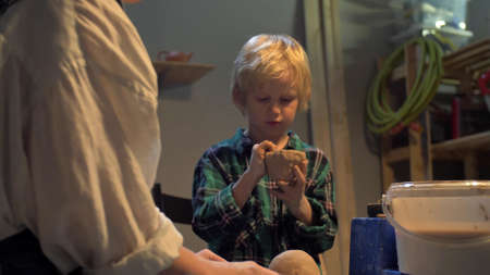 Boy sculpts a cup with his hands in the workshopの写真素材