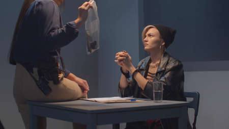 A cop shows a woman a gun as evidence. View