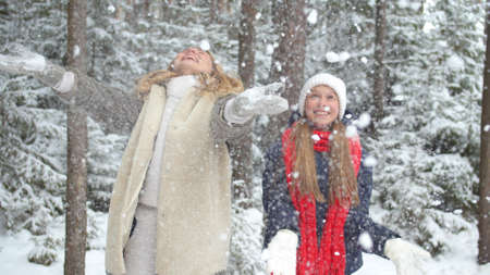 Mom and daughter throw snow over themselves