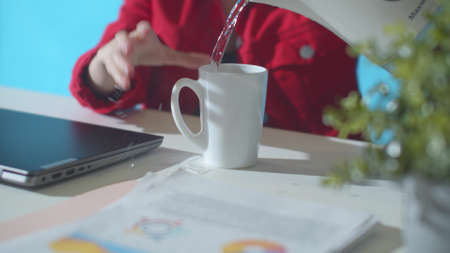 Office worker pours water past the mug. Close upの写真素材