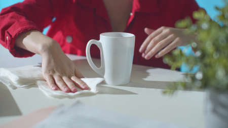 Office worker wipes water that spilled from a mug onto a tableの写真素材