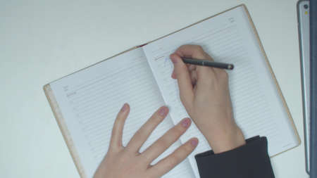A man closes a laptop and takes out a notebookの写真素材
