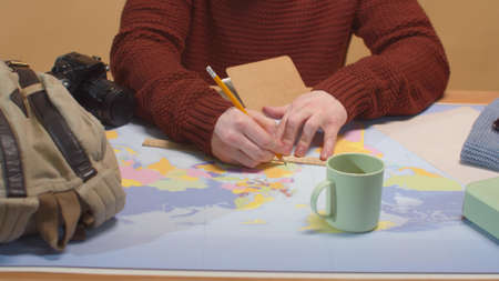A man draws on a map on a ruler. Close up