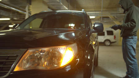 Car thief hacks a car using a tablet and sits in itの写真素材