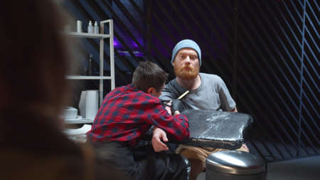 A girl watches a guy get a tattoo. Backgroundの写真素材