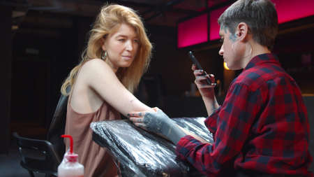 Tattoo master photographs on the phone his new workの写真素材