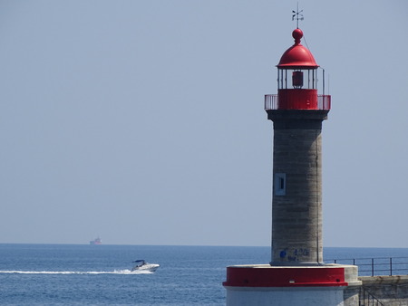 view of the harbor entrance lighthouse in front of the sea horizonの写真素材