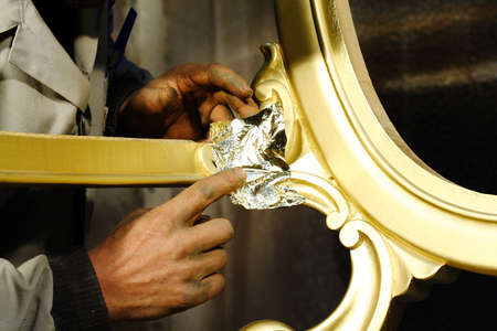 Hands working on wood with gold filmの写真素材