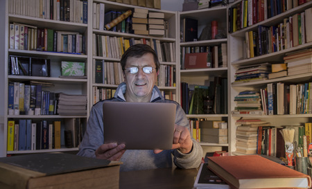 Mature man surrounded by books but read on your tabletのeditorial素材