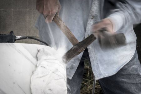 Detail of artist's hands sculpting marble with hammer and chiselの写真素材